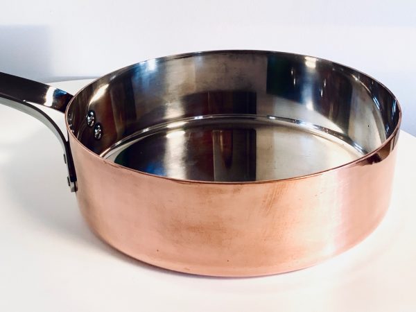 Afbeelding van een koperen sauteerpan van Georg Jensen ontworpen door Henning Koppel die in deze advertentie wordt aangeboden.